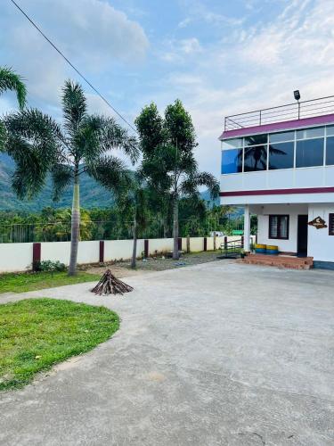 un bâtiment avec des palmiers en face de celui-ci dans l'établissement Kadampil Bliss, à Maraiyūr