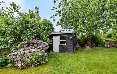 a small black shed in a yard with flowers at 3 Bedroom Gorgeous Home In Hornbæk in Hornbæk