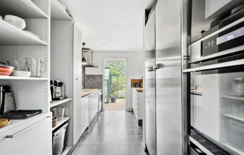 a kitchen with white cabinets and a large refrigerator at 3 Bedroom Gorgeous Home In Hornbæk in Hornbæk