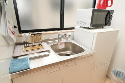 a kitchen counter with a sink and a microwave at 三十三Kin in Kyoto