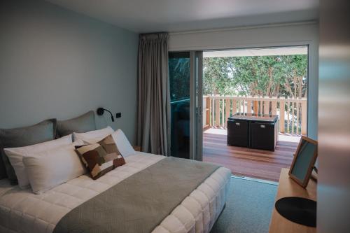 a bedroom with a bed and a sliding glass door at Golden Bay Holiday Park in Onekaka