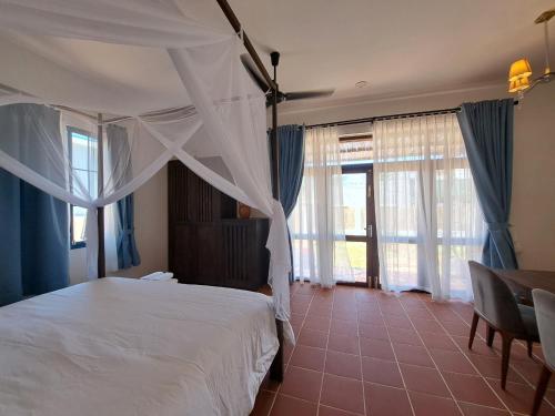 a bedroom with a white bed with blue curtains at La nho House in Ninh Hải
