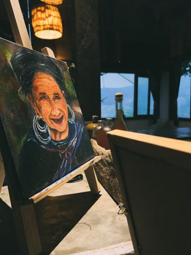 a painting of a man sitting on a easel at Pavi garden in Sa Pa