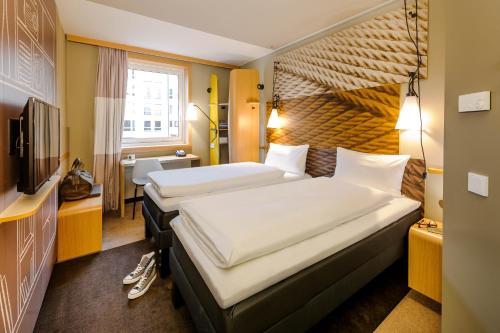 ミュンヘンにあるアイビス ミュンヘン シティ アルヌルフパークのベッド2台とテレビが備わるホテルルームです。