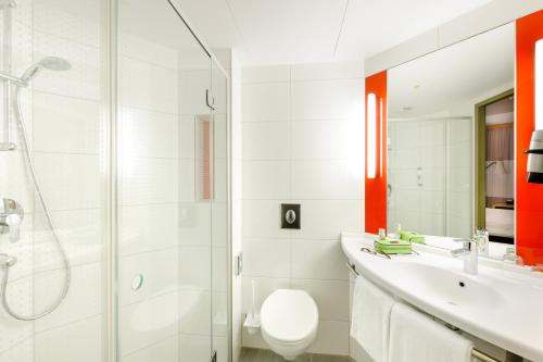 a bathroom with a toilet and a sink and a shower at Ibis München City Arnulfpark in Munich