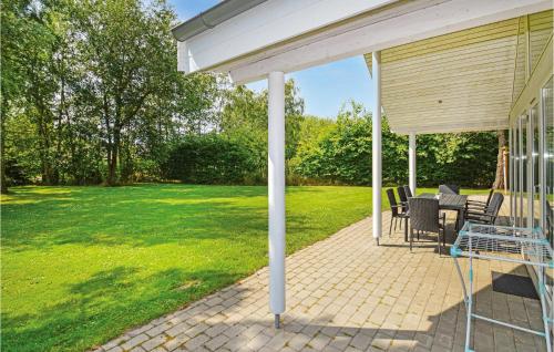 a covered patio with a table and chairs at Beautiful Home In Væggerløse With Sauna in Marielyst
