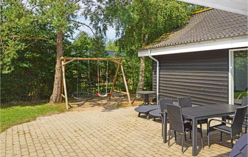 a patio with a table and chairs and a playground at Beautiful Home In Væggerløse With Sauna in Marielyst