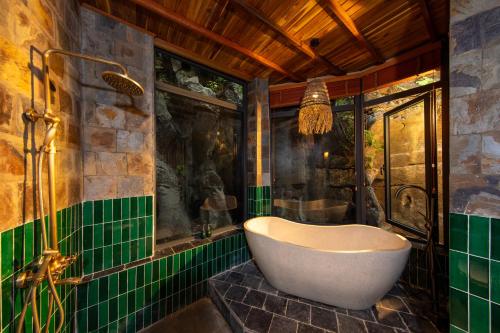 een badkamer met een bad en groene tegels bij Mua Caves Ecolodge (Hang Mua) in Ninh Binh