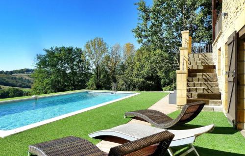 a swimming pool with two chairs next to a house at La Poujade in Sarlat-la-Canéda