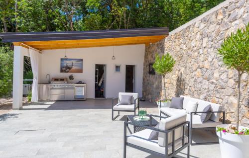 a patio with a table and chairs and a stone wall at Awesome Home In Bribir With Jacuzzi in Bribir