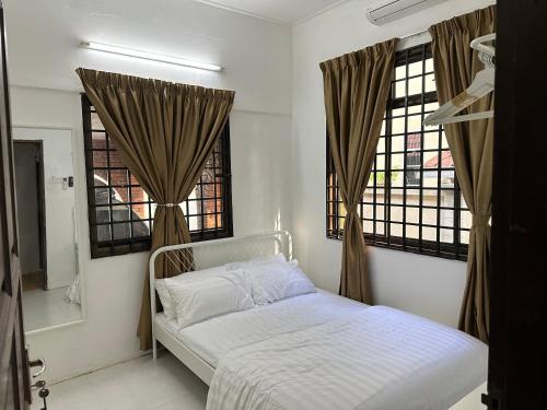 a bedroom with a bed and two windows at Mawar 23 Chendering with Private Pool in Kuala Terengganu