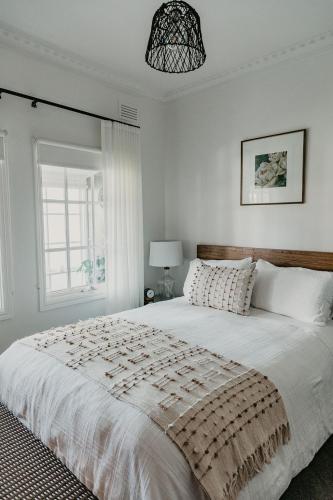 a bedroom with a large white bed with a window at Edge17 Waterfront Apartment, plus Cottage with Garden View - Port Fairy in Port Fairy
