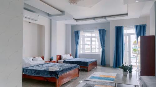 a bedroom with two beds and blue curtains at Miha Villa Can Tho in Can Tho