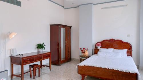 a bedroom with a wooden bed and a desk at Miha Villa Can Tho in Can Tho