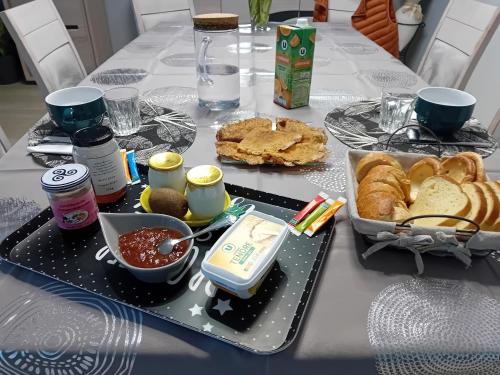 einen Tisch mit einem Tablett mit Essen und Brot darauf in der Unterkunft Cœur de ville, chambre confortable à louer en Bretagne in Saint-Méen-le-Grand