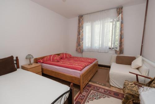 a bedroom with two beds and a couch and a window at Pensiunea La Maison Verte in Pietroasa