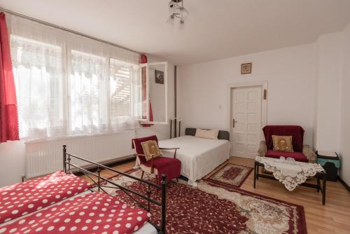 a bedroom with a bed and two chairs and a window at Pensiunea La Maison Verte in Pietroasa