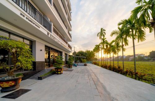 une passerelle à l'extérieur d'un bâtiment planté de palmiers dans l'établissement Eco Lux Riverside Hotel & Spa, à Hội An