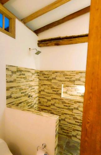 a bathroom with a shower with a stone wall at Cabañas Barikoke-Capri in Moñitos