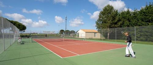 un garçon tenant une raquette de tennis sur un court de tennis dans l'établissement Studio cosy maison neuve Rafa, à Médis
