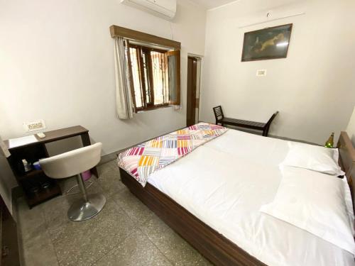 a bedroom with a bed and a desk and a chair at Garden View Residency, Deluxe Queen Room 1 in Lucknow