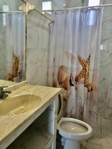 a bathroom with a shower curtain with a toilet and a sink at LA PUCCA HOTEL BOUTIQUE RESORT in La Peñita de Jaltemba
