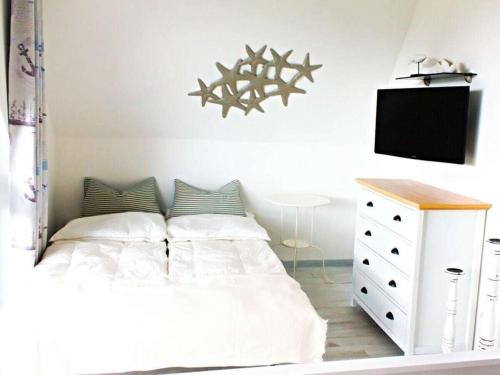a bedroom with a white bed and a tv at Starfish Comfortable holiday residence in Vieregge