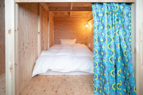 a bed in a small room with a curtain at métisse stay in Nanto
