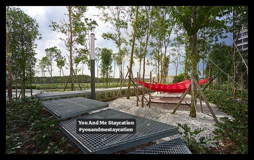 a red hammock in a park with trees at Luge Gardens You and Me Staycation Gaia Residences in Rawang