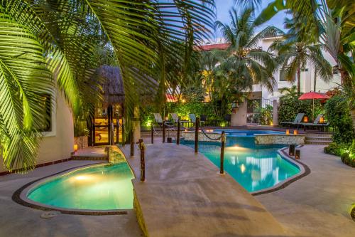 a resort pool with palm trees and a building at Hotel Riviera Del Sol in Playa del Carmen