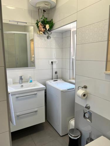 W białej łazience znajduje się umywalka i lustro. w obiekcie Apartment Fonte w Splicie