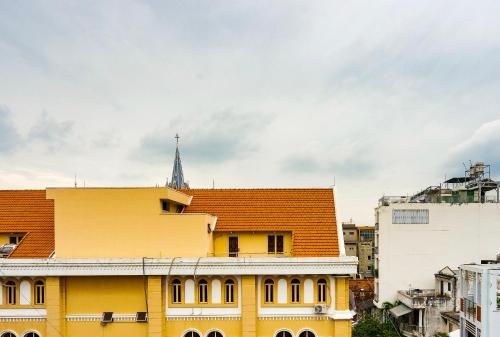 a yellow building with a red roof in a city at HemTouch House in Ho Chi Minh City