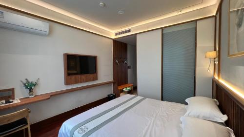 a hotel room with a bed and a tv at 嵩山居-丽晶精品民宿 in Dengfeng