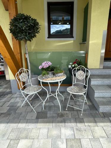 2 sillas y una mesa con flores en el patio en Haus Laubreuter en Kaprun