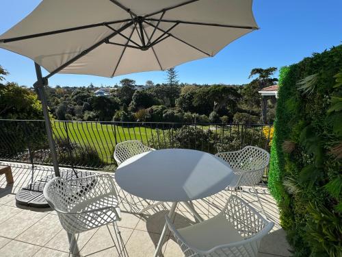 a table and chairs with an umbrella on a patio at Waiake Beach Apartments in Auckland