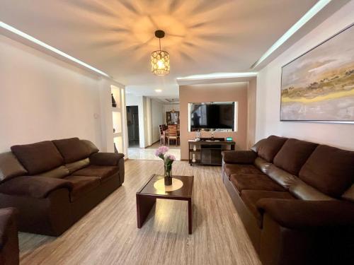 a living room with two brown couches and a tv at Martita's Home in Loja