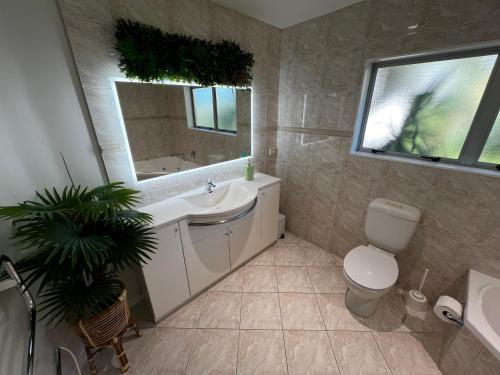 a bathroom with a sink and a toilet and a mirror at Waiake Beach Apartments in Auckland