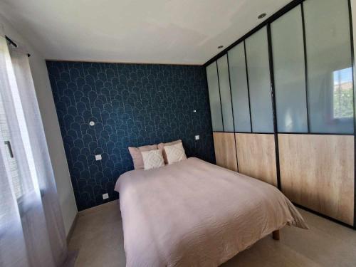 une chambre avec un lit et un mur bleu dans l'établissement Paisible villa plain pied 110m2, à Saint-Nazaire