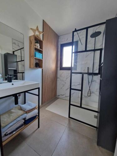 une salle de bain avec un lavabo et une douche avec un miroir dans l'établissement Paisible villa plain pied 110m2, à Saint-Nazaire