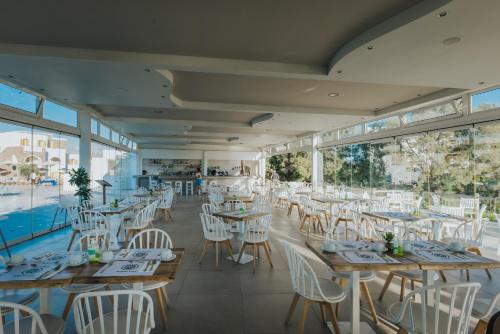 a restaurant with tables and white chairs and windows at Aegean Palace in Plaka