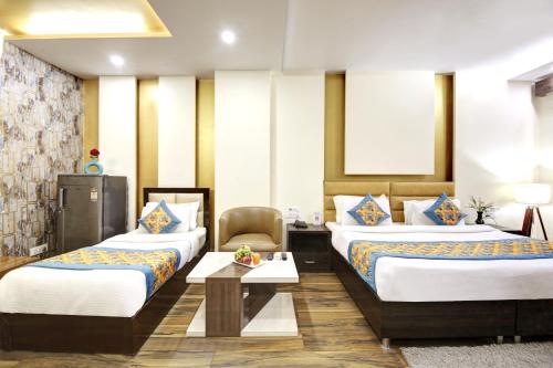 a hotel room with two beds and a table at Hotel Grand Manor in Gurgaon