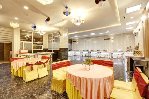 a banquet hall with two tables and yellow chairs at Hotel Grand Manor in Gurgaon