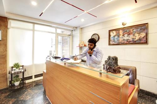 a woman standing behind a counter talking on a cell phone at Hotel Grand Manor in Gurgaon
