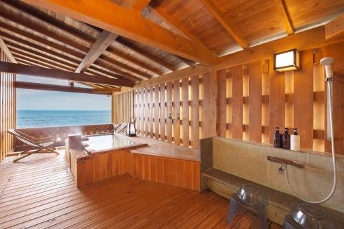a large wooden room with a bath tub and the ocean at Senoumi in Higashiizu