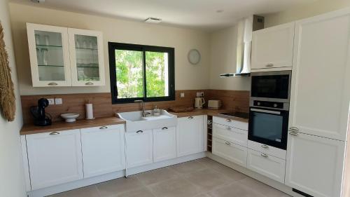 a kitchen with white cabinets and a sink and a window at L'éden des Baronnies in Mirabel-aux-Baronnies