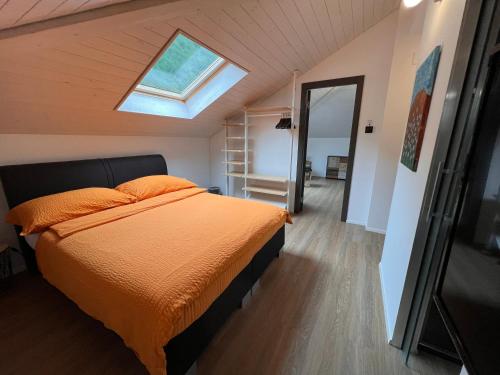 una camera da letto con un letto con lenzuola arancioni e un lucernario di B&B Cà Nosa a Gordevio