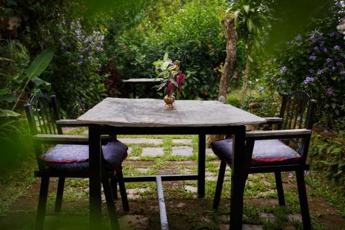 a table with two chairs and a vase on it at The Famous Farm in Nawākot