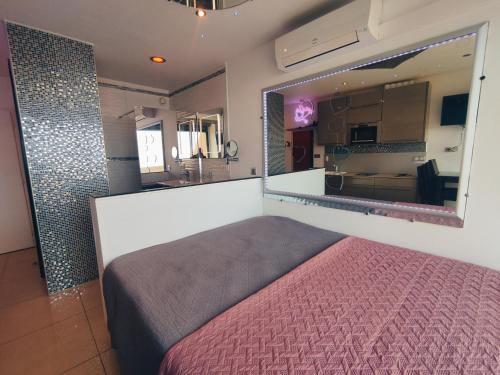 une chambre avec un lit et un grand miroir dans l'établissement Studio 404 Héliopolis naturiste, au Cap d'Agde