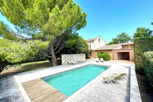une piscine avec deux chaises et une maison dans l'établissement Le Mas de L'Olivier, à Saint-Maurice-sur-Eygues