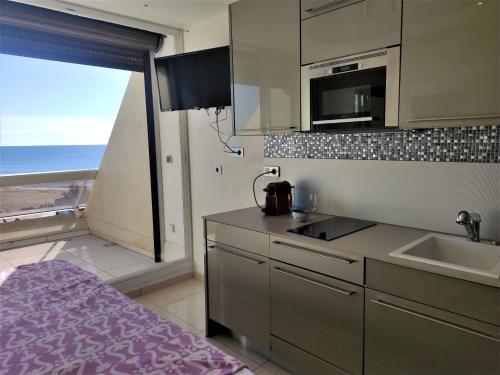une cuisine avec évier et four micro-ondes ainsi qu'une fenêtre dans l'établissement Studio 404 Héliopolis naturiste, au Cap d'Agde